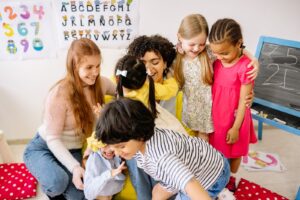 Happy pre-school children sitting with an early years practitioner