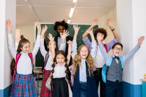 Primary school children raising their hands in a classroom